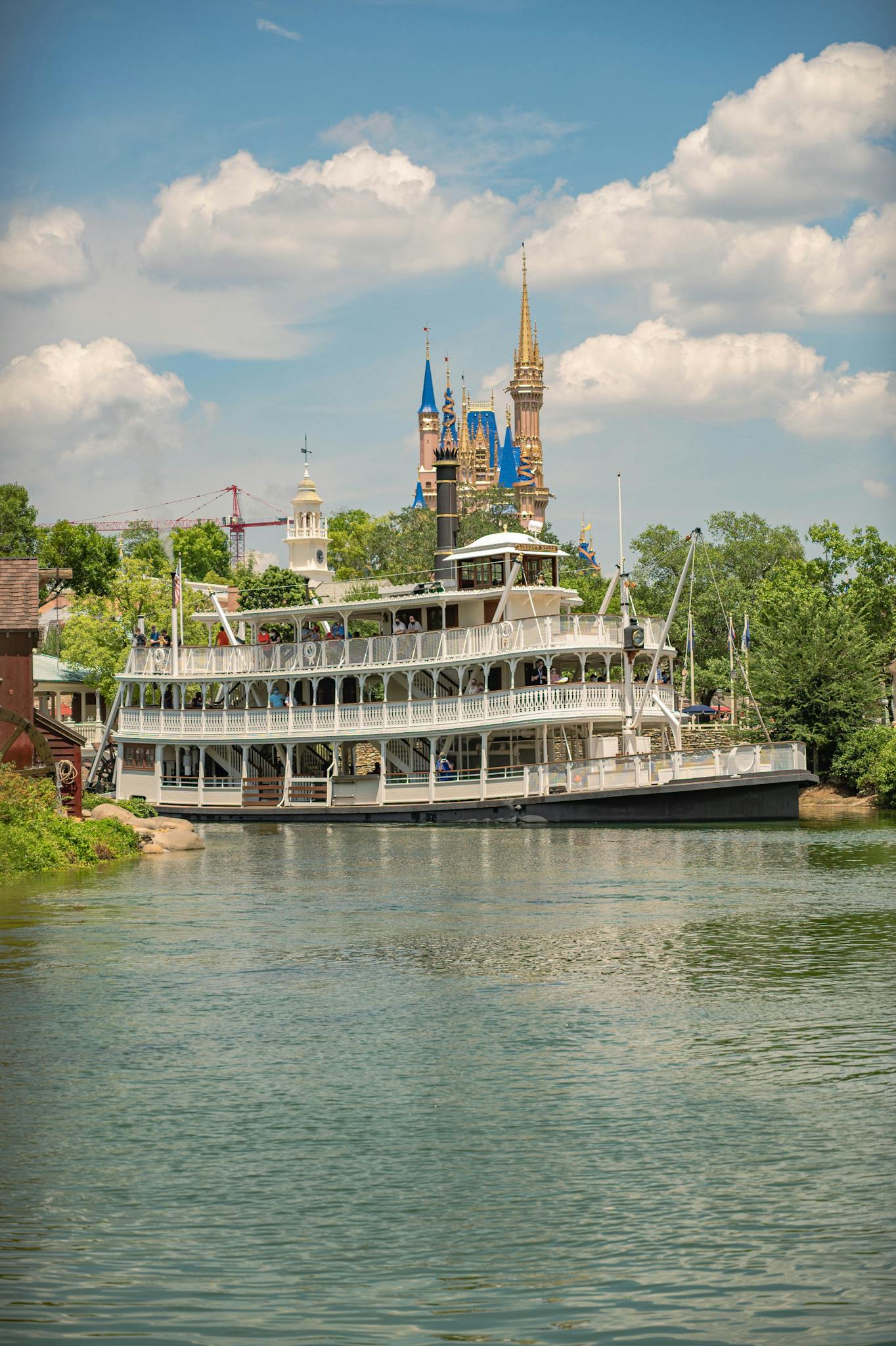 A picturesque riverboat cruising along a scenic waterway beside a fairytale castle under a summer sky.