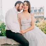 A romantic photo of newlyweds sitting together with the iconic Eiffel Tower in the background.