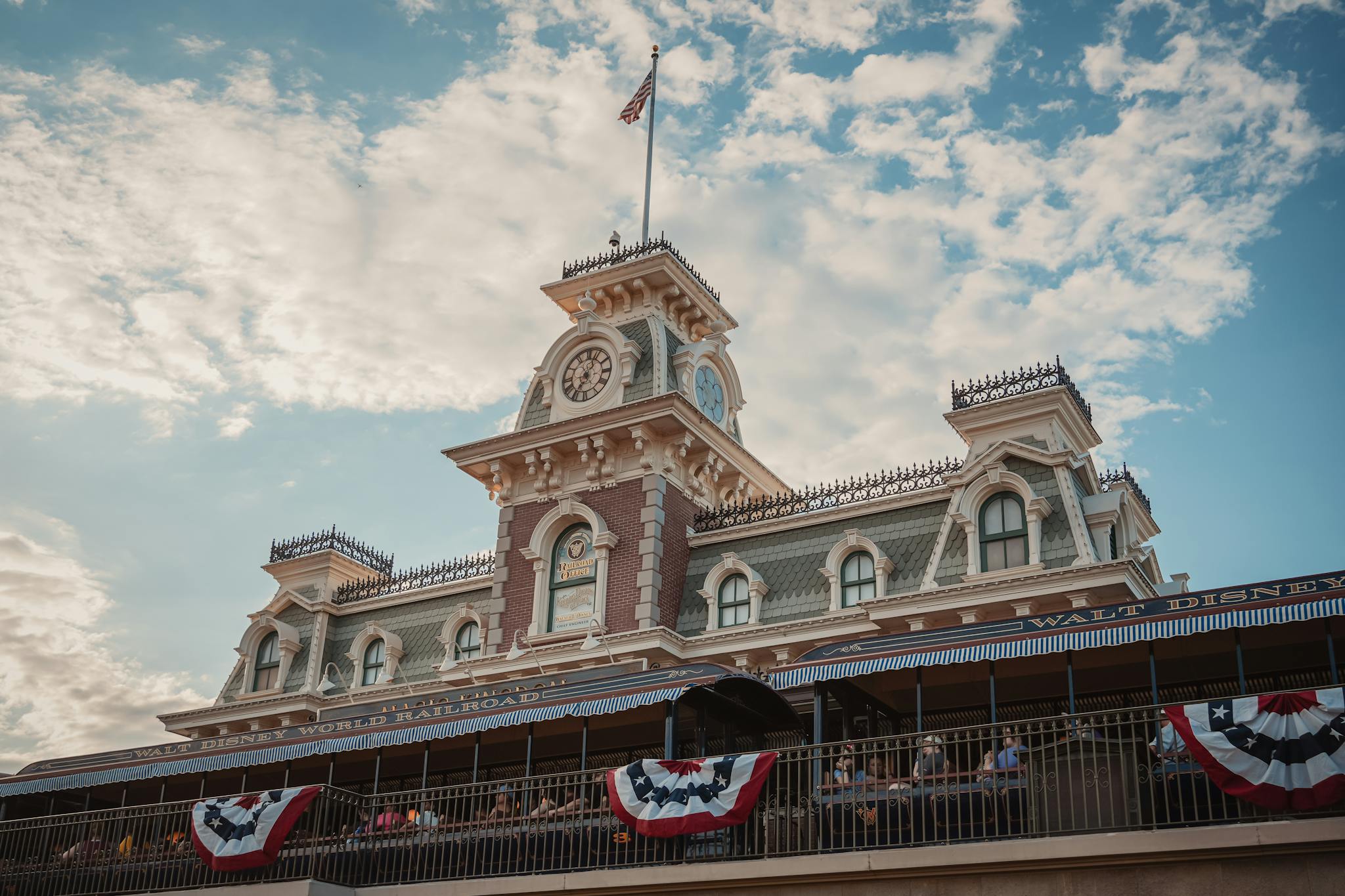 Iconic entrance to Walt Disney World Railroad at Magic Kingdom, Orlando, Florida, with vintage architecture and American flags.