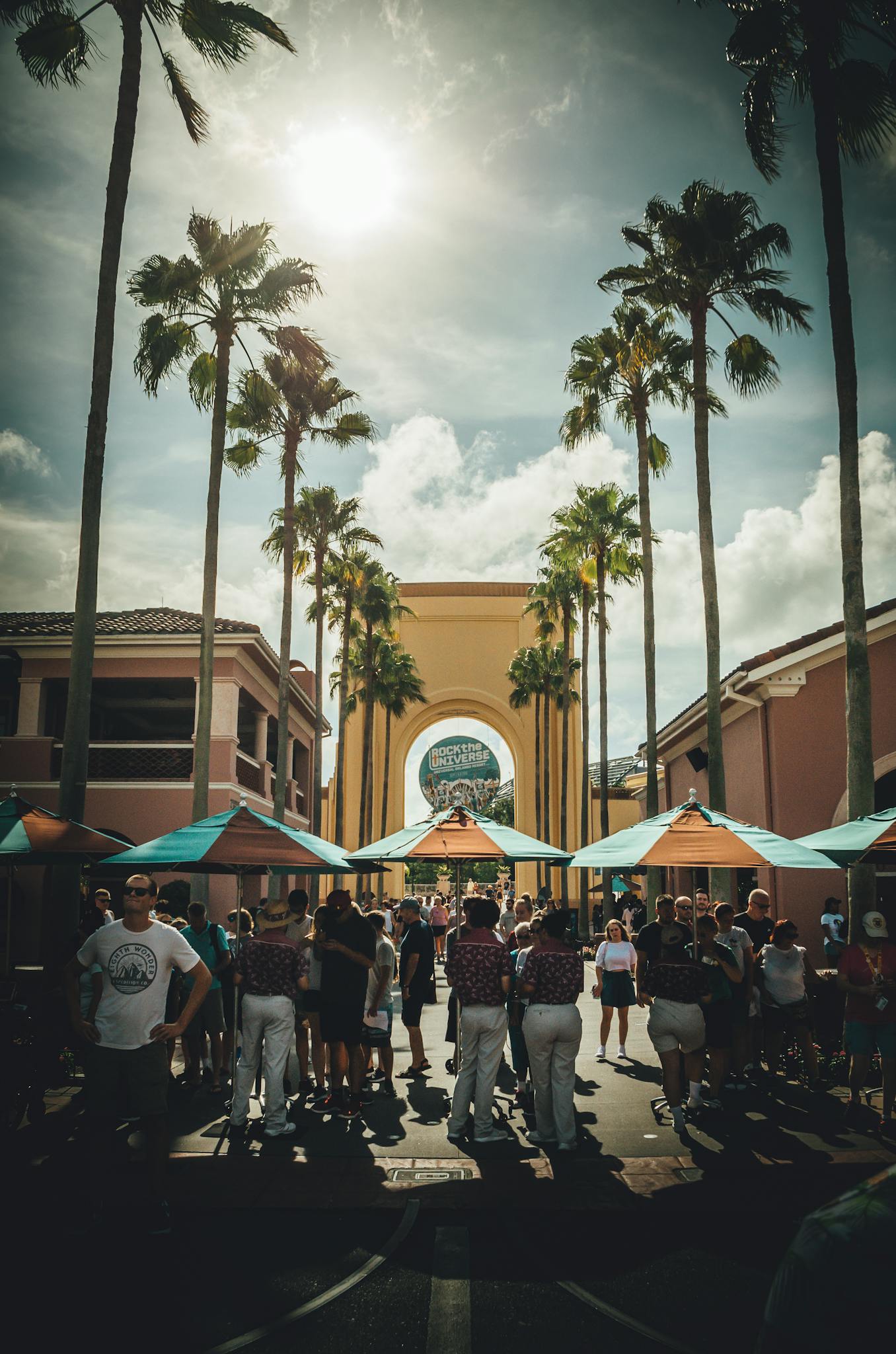 Tourists gather at a popular Orlando theme park entrance on a sunny day.